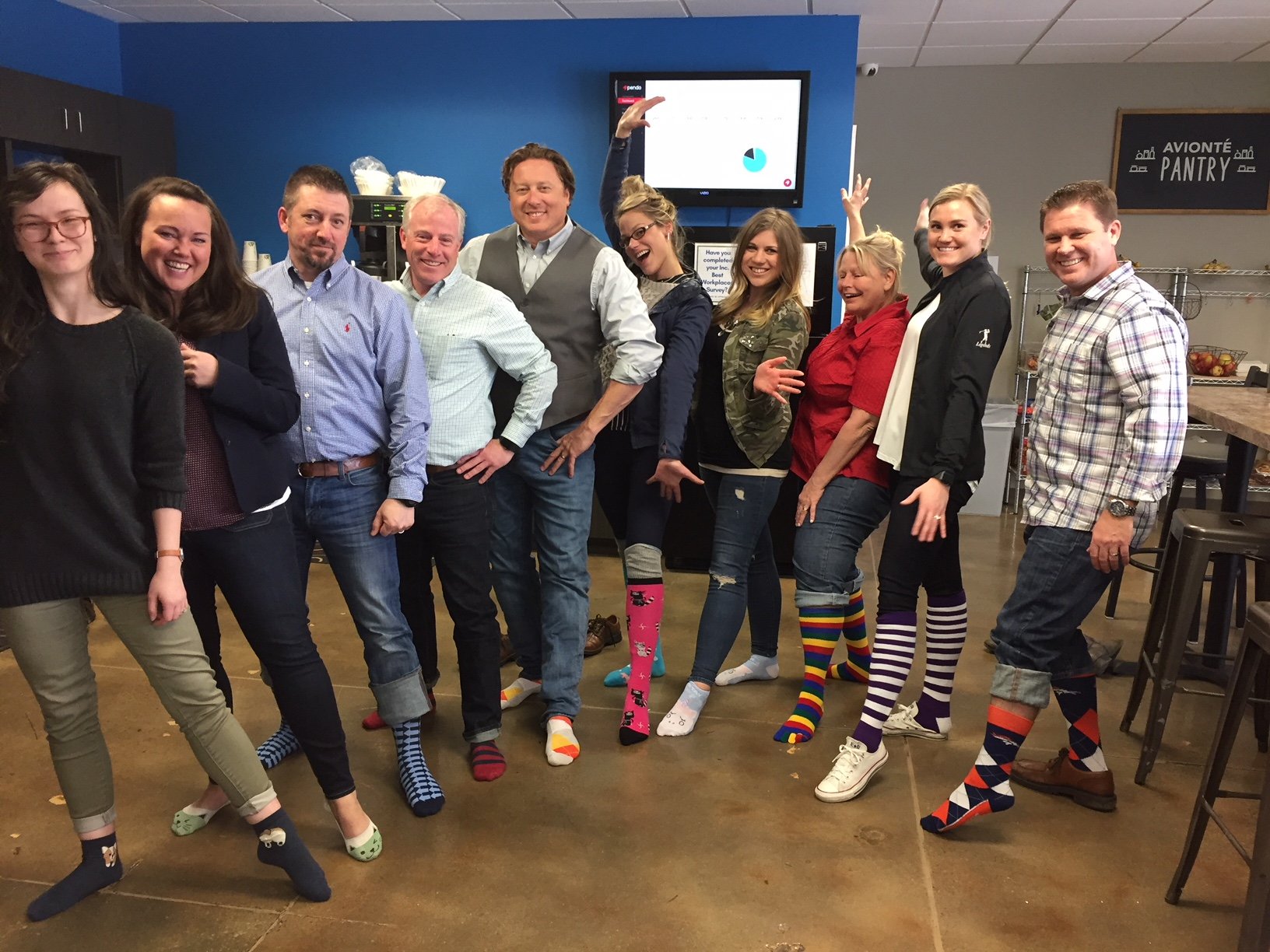 Avionté employees wearing silly socks and posing in the breakroom