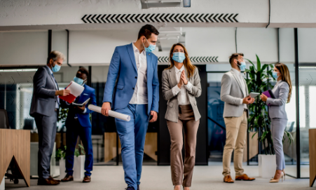 People in an office setting standing wearing masks